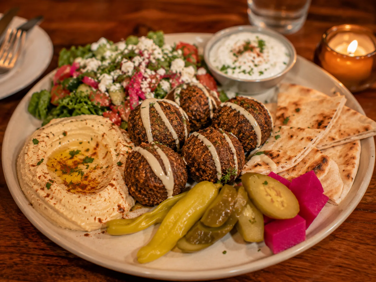 Falafel platter with hummus, pita, salad, pickles, and tahini sauce