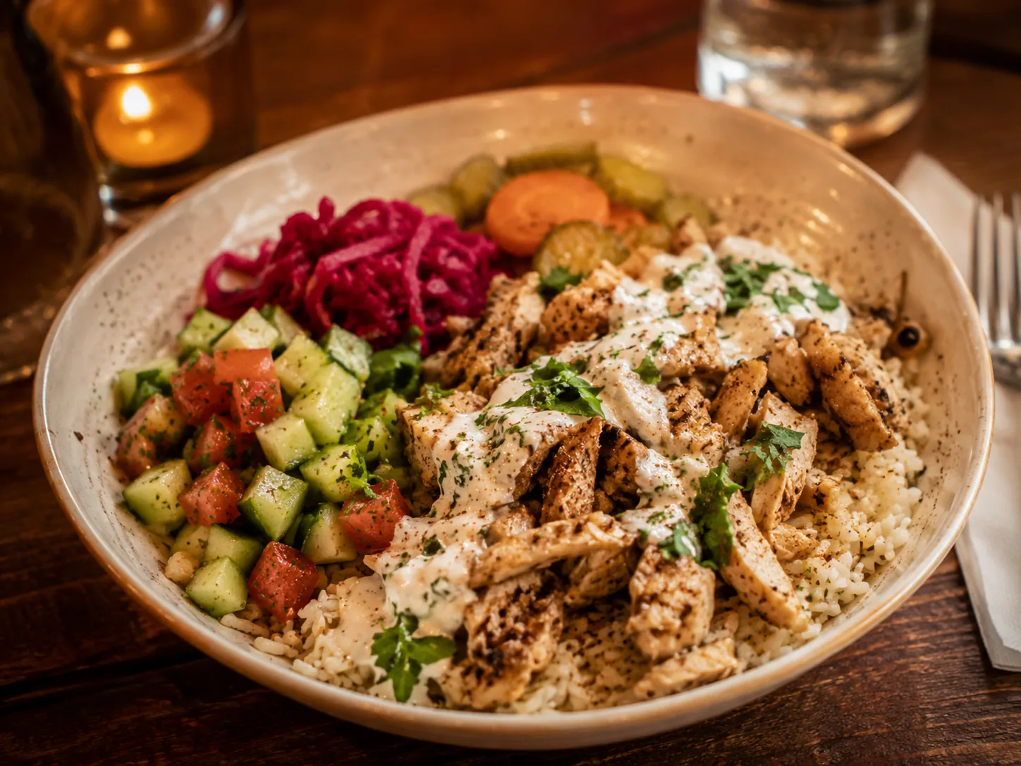 Mediterranean rice bowl with grilled chicken, vegetables, herbs, and garlic sauce