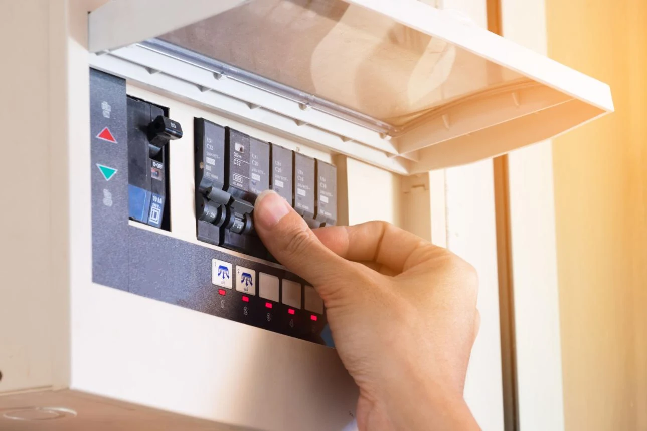 A hand resetting a home electrical breaker panel.