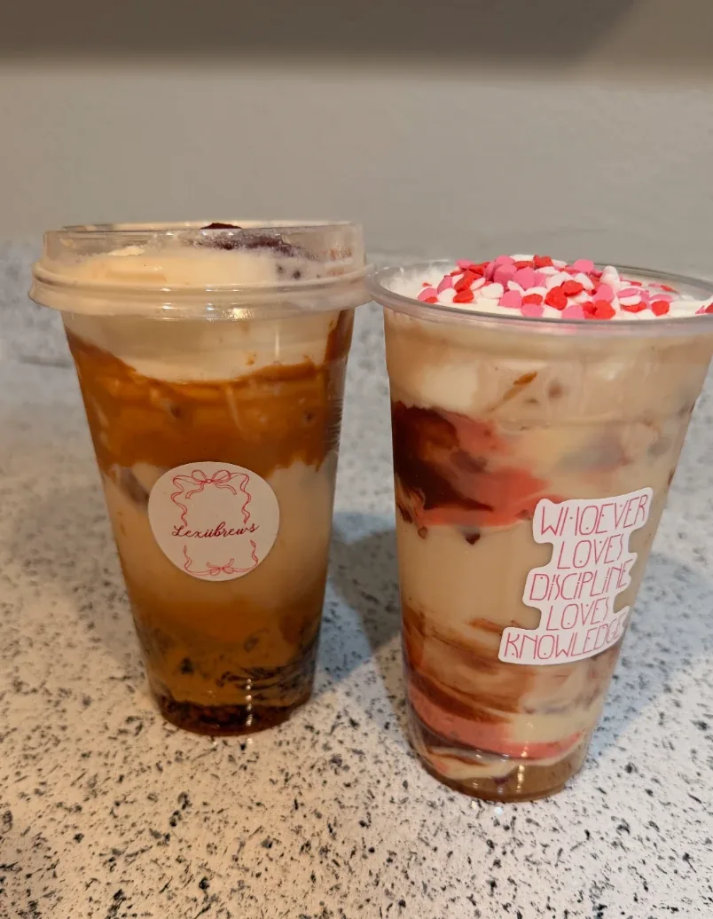 Two LexiBrews iced coffees with creamy swirls and pink topping accents
