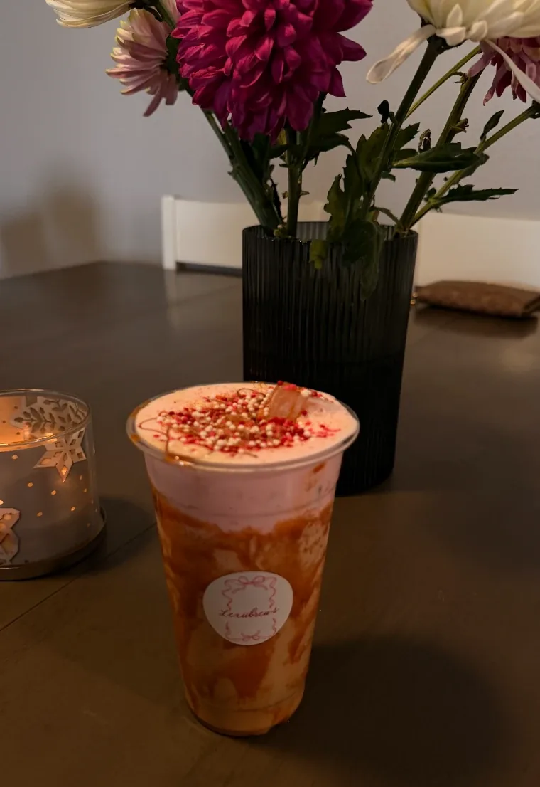 A LexiBrews layered iced coffee styled on a table with flowers and candlelight